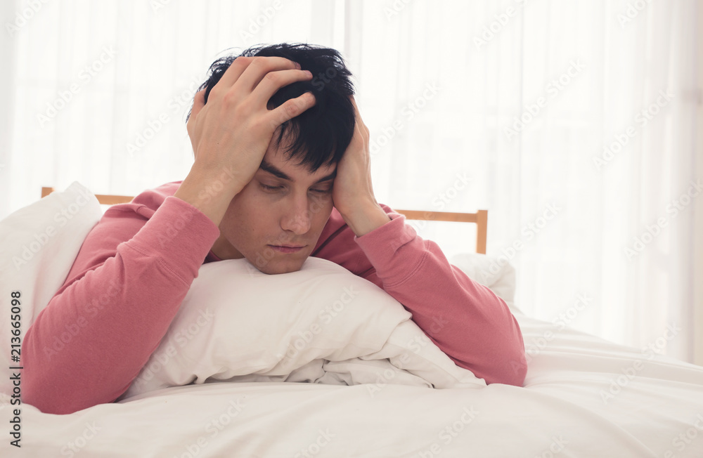 Young Caucasian man in bed with headache with lack Young Caucasian man in bed with headache with lack