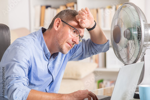 Man suffers from heat in the office or at home photo