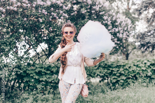 Portrait of a Smiling Beautiful Lady in Sunglasses Holding Cotton Candy at Park and Happily Looking in Camera. Film Color and Toning