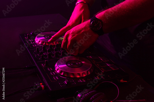 Dj mixing on turntables with color light effects. Soft focus on hand. Close-up.