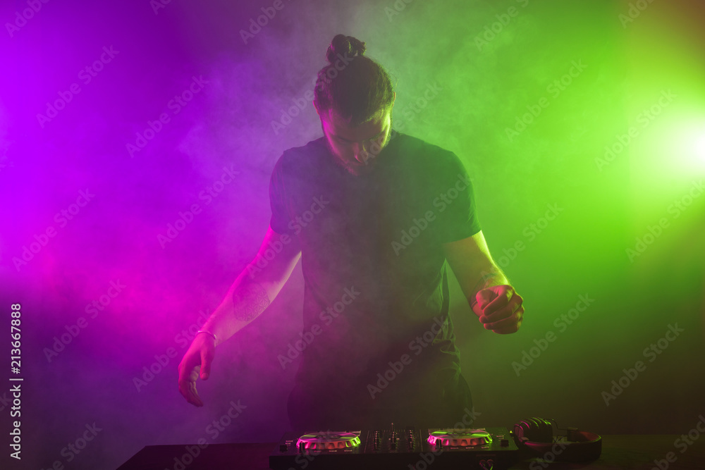 DJ at work mixing sound on her decks at a party or night club with  colourful smoke light background Stock Photo | Adobe Stock