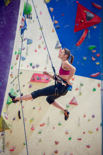 Photo of young girl with talc bag behind back practicing on climbing wall
