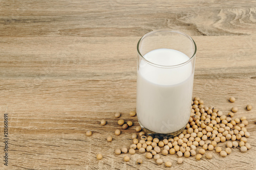 a glass of soy milk and a pile of soybeans on the wooden table.