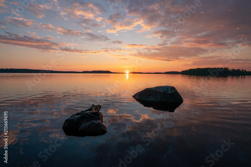 Very beautiful landscape image of a sunset behind calm mirror clear lake