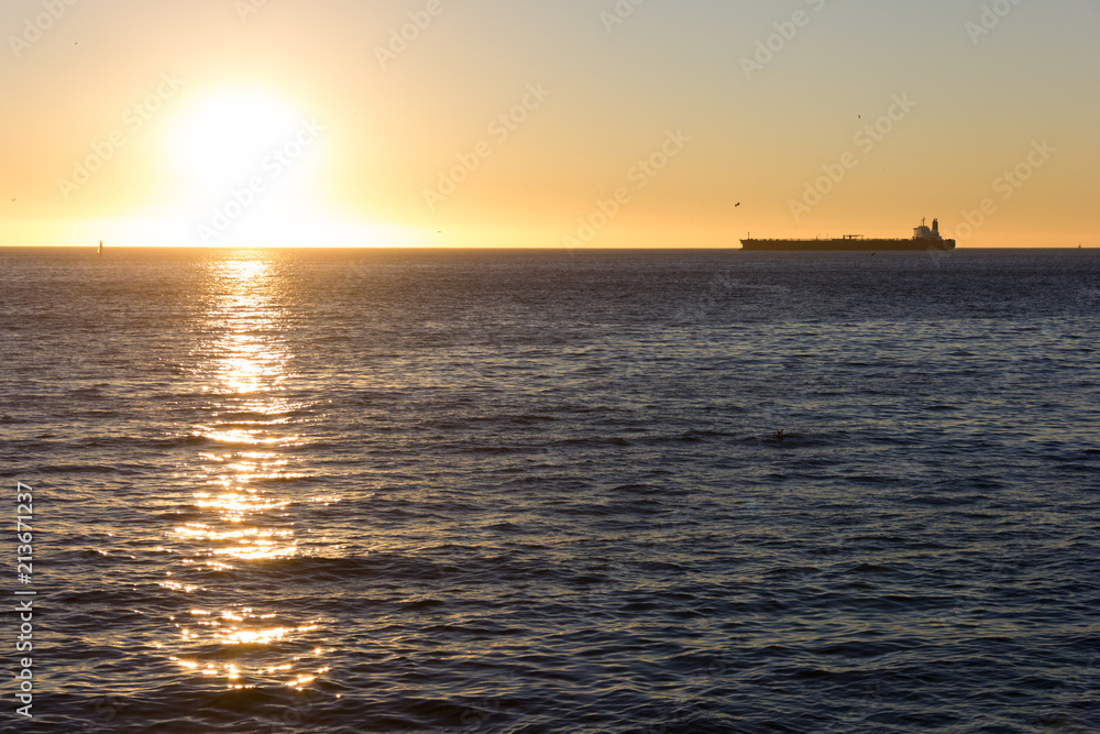 Cargo ship on the horizon at sunset heading to Valparaiso pier, Chile. International transportation, shipping concept