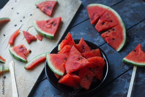 Fresh organic watermelon slice popsicles on rustic wooden board and dark rustic wooden background. Selective focus. Tasty summer fruit, healthy lifestyle