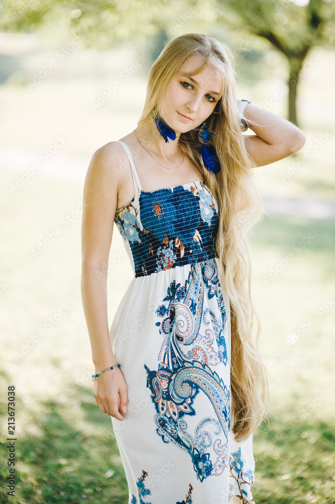 portrait of a young woman with long hair in a dress breathing fresh air on a sunny summer day