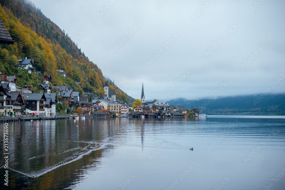 Foggy autumn view of Hallstatt lake, mountains and village with houses and church in Austria. Beautiful countryside in autumn.