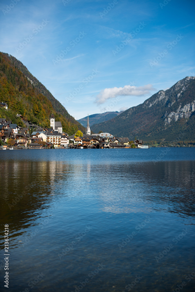 Scenic autumn view of Hallstatt lake, mountains and village with houses and church in Austria. Beautiful countryside in autumn.