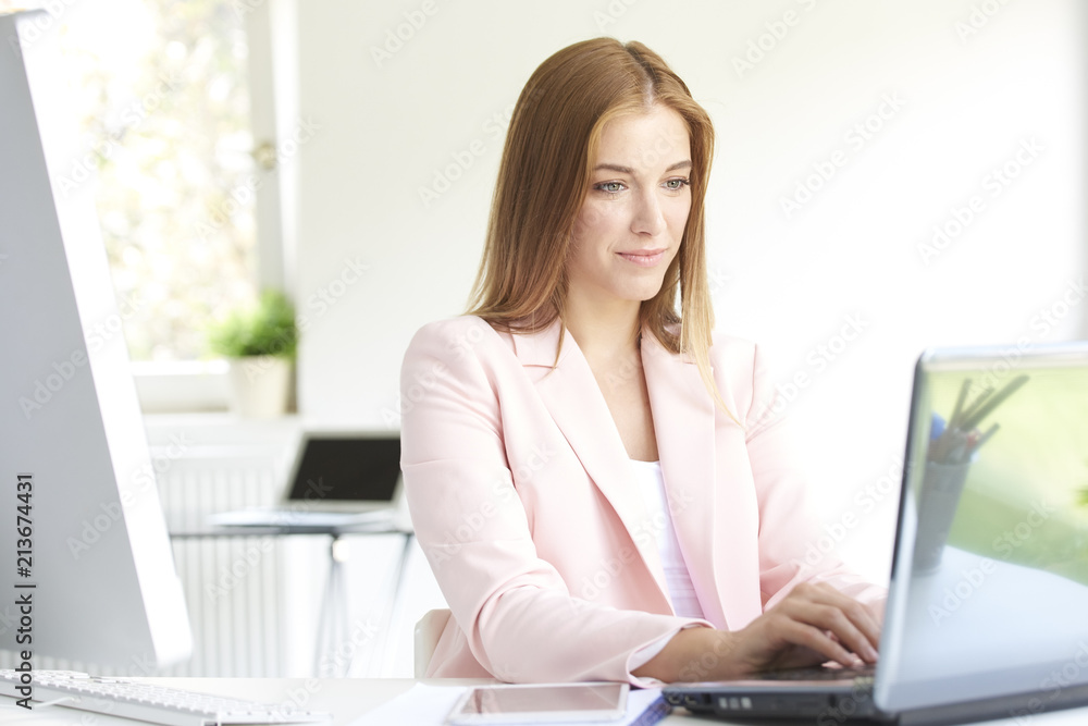Smiling young businesswoman using laptop at office Smiling young businesswoman using laptop at office