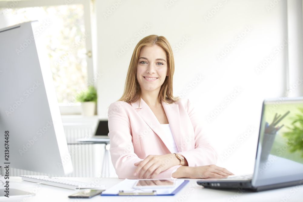 Smiling young businesswoman using laptop at office Smiling young businesswoman using laptop at office