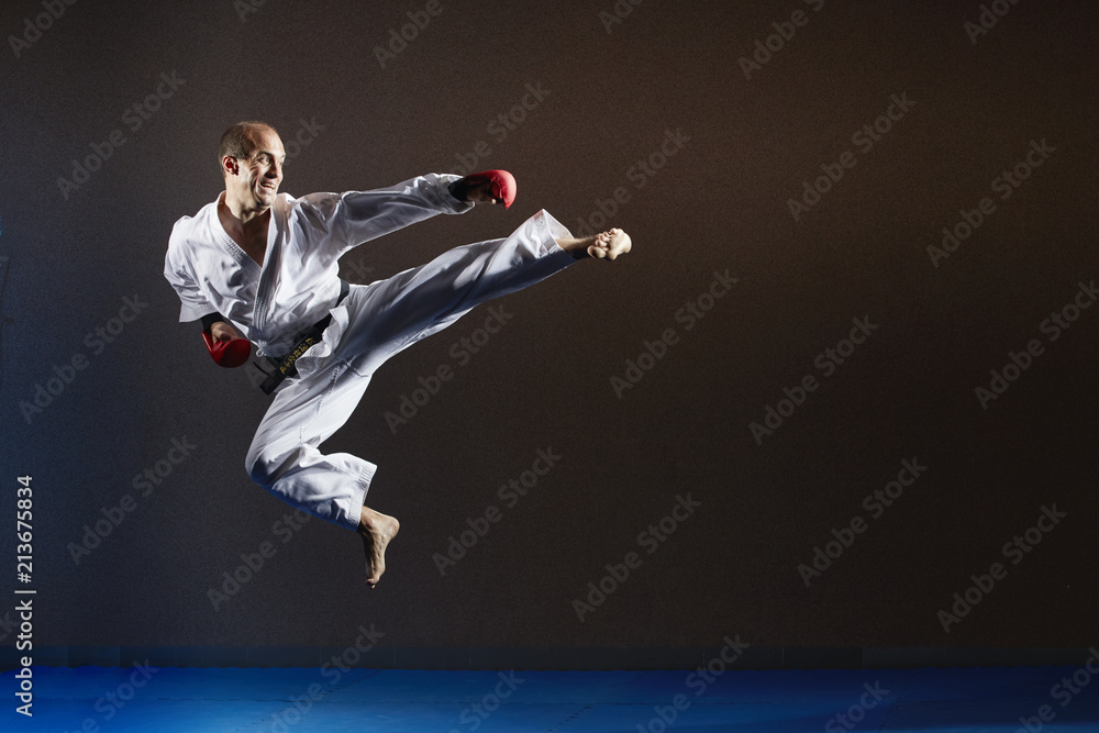 An athlete in karategi in a jump beats a kick to the side