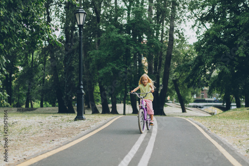 adorable blond child riding bicycle on road in park