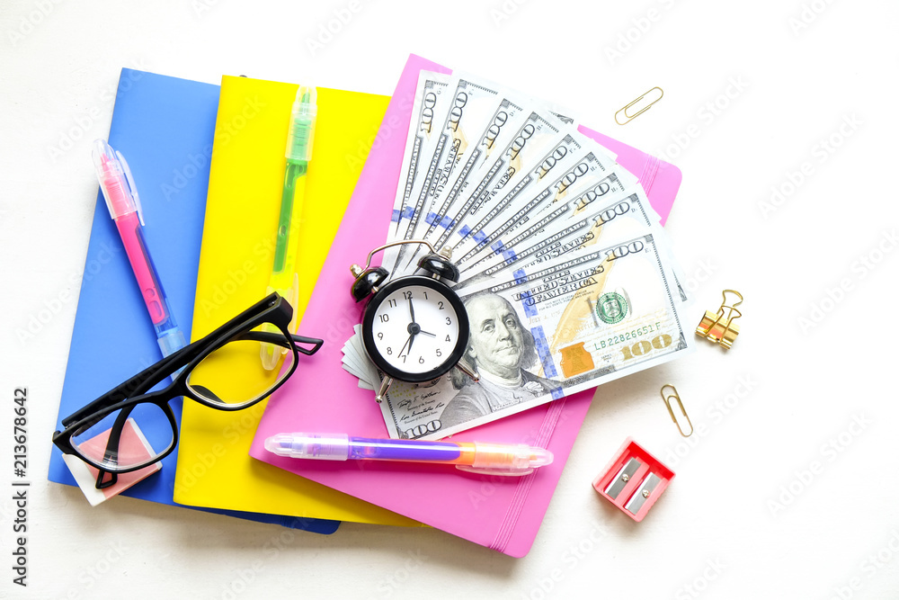 Investing time & money in expensive education, college tuition & fees  concept. Pack of new one hundred dollar bills, notebooks, school supplies,  alarm clock. Background, copy space, close up, flat lay Stock