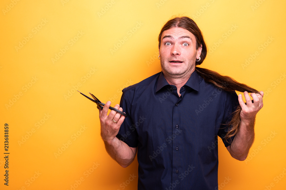 Man with despaired look thinking of cutting hair with scissors