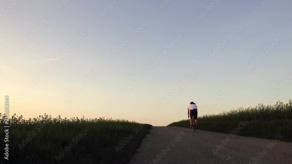 Cyclist rides on a road after sunset Cyclist rides on a road after sunset
