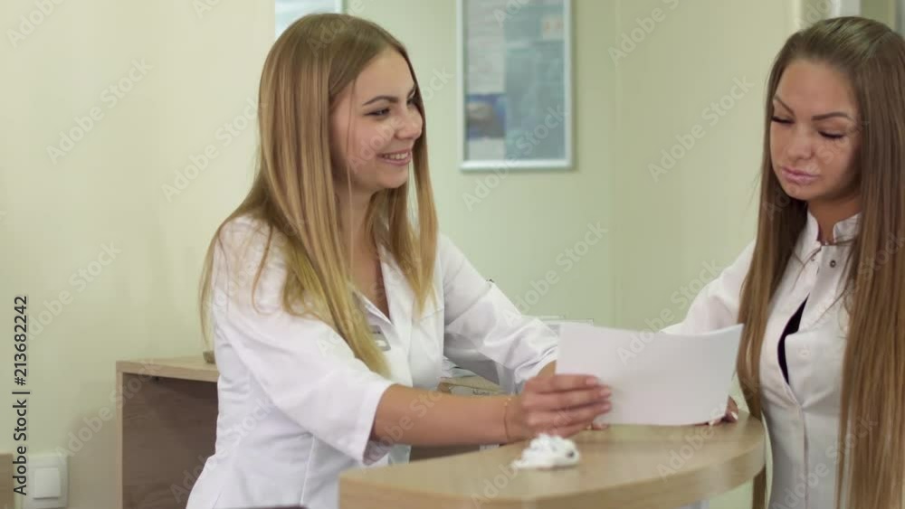 Two young nurses discussing disease history of patient Two young nurses discussing disease history of patient
