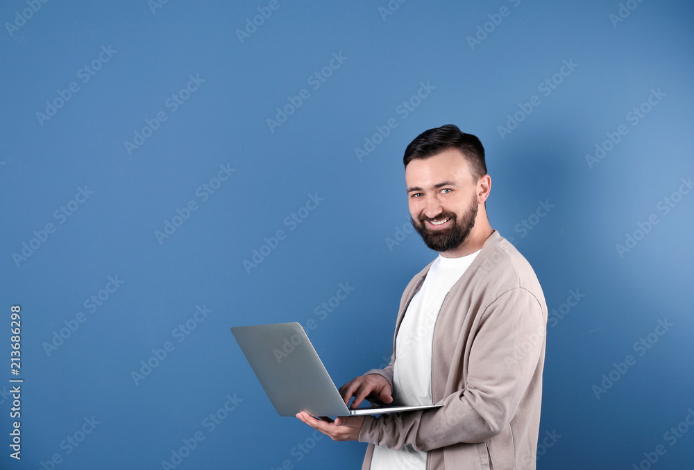 Portrait of handsome bearded man with laptop on color background Portrait of handsome bearded man with laptop on color background