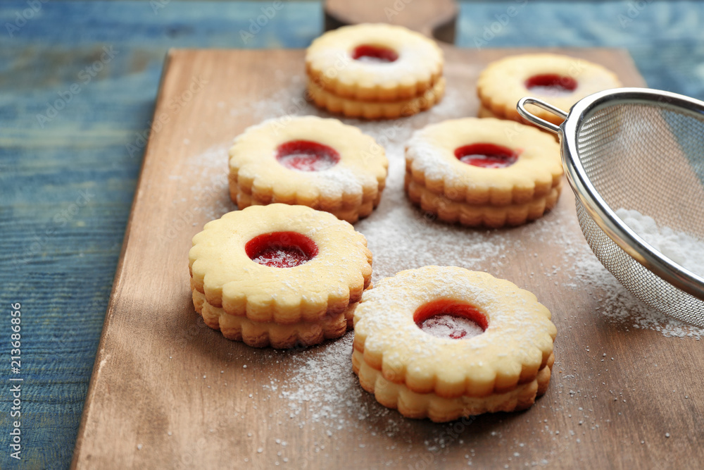Traditional Christmas Linzer cookies with sweet jam and sugar powder on wooden board