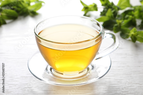 Cup with hot aromatic mint tea on table