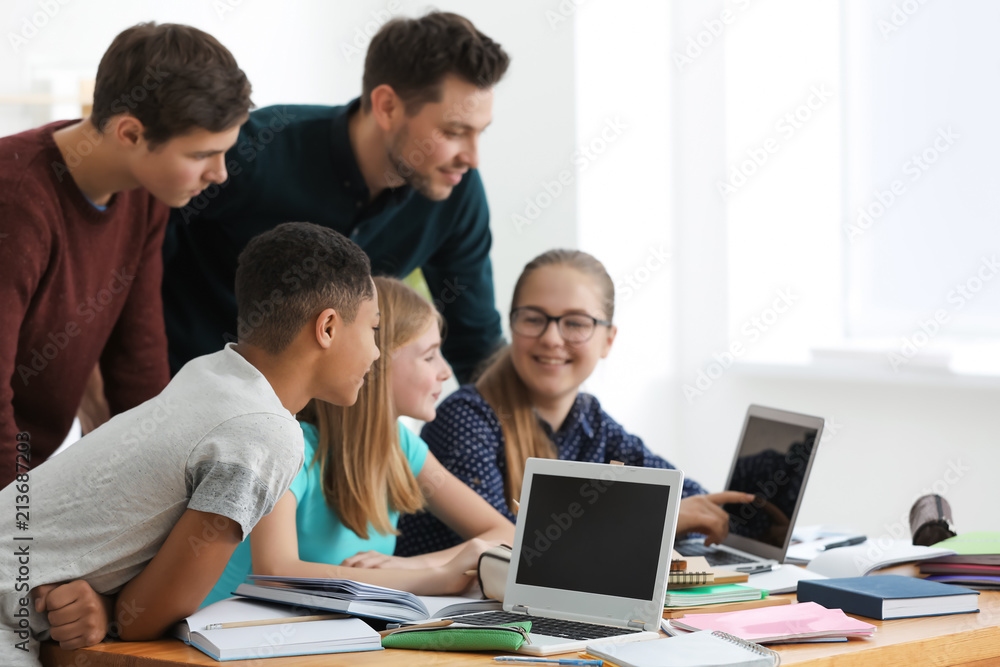 Group of teenagers doing homework with teacher in classroom Group of teenagers doing homework with teacher in classroom