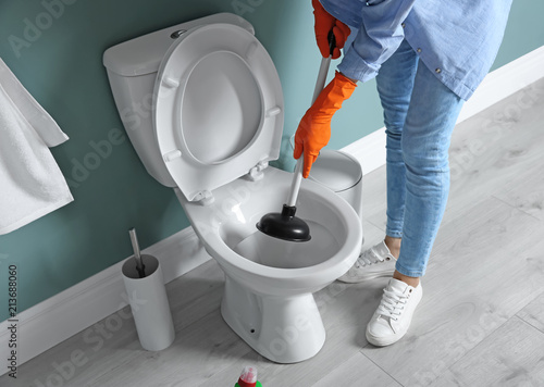 Woman cleaning toilet bowl in bathroom