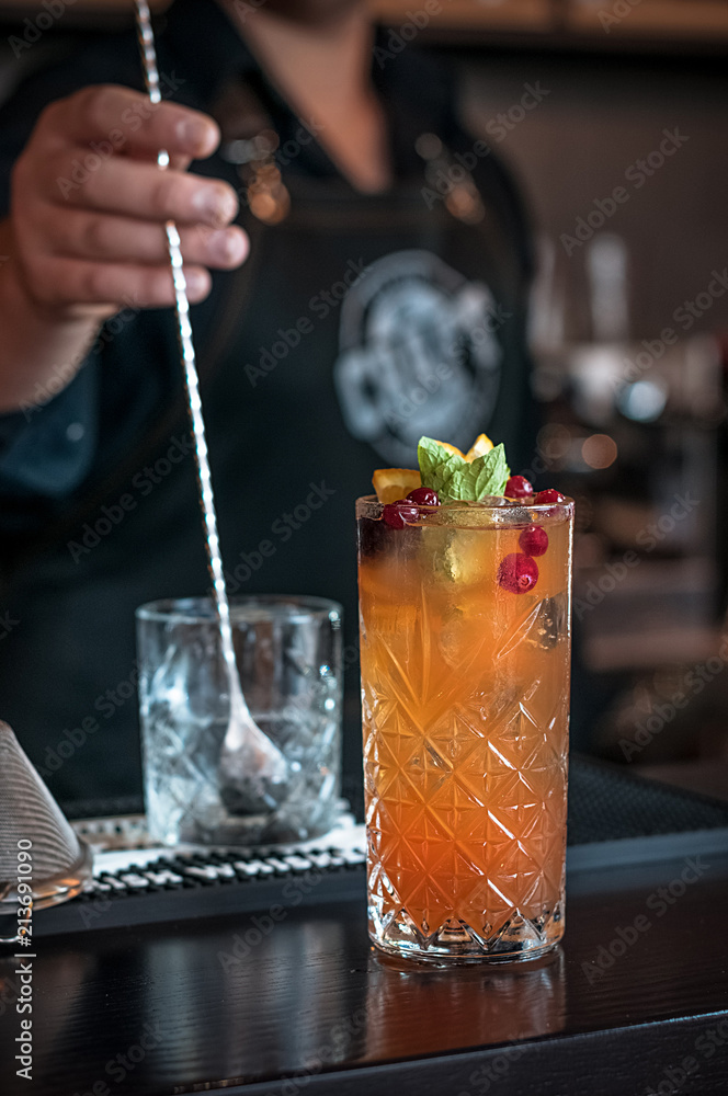 bartender barmen with cocktail preparing orange cocktail at bar