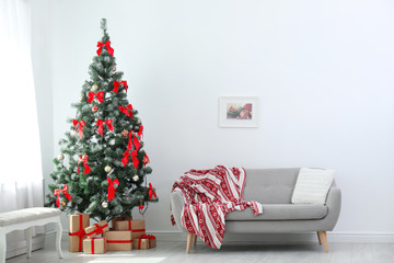 Stylish living room interior with decorated Christmas tree and comfortable sofa