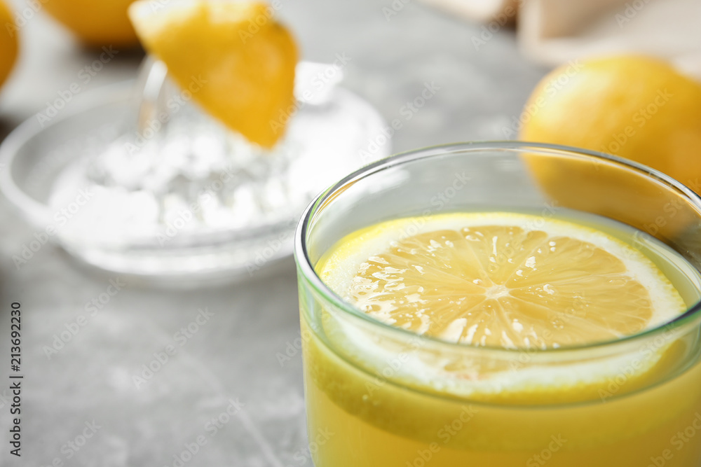 Glass with fresh lemon juice on table, closeup Glass with fresh lemon juice on table, closeup