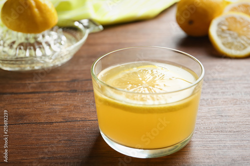 Glass with fresh lemon juice on wooden table