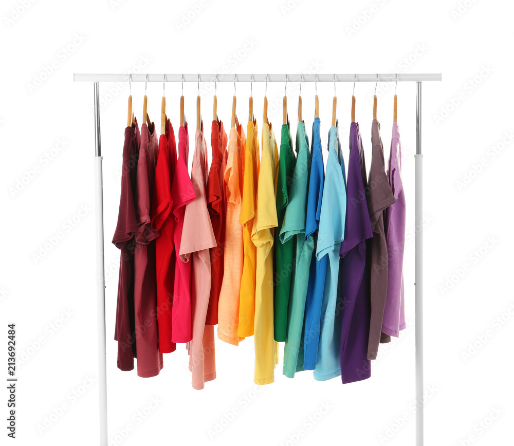Many t-shirts hanging in order of rainbow colors on white background