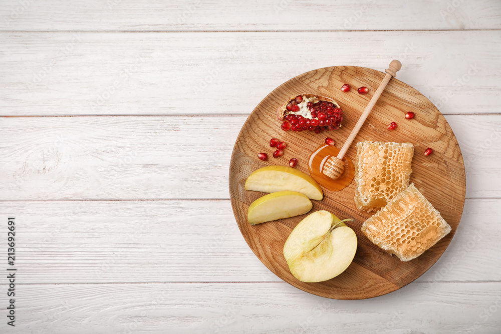 Flat lay composition with honey, dipper, sliced apples and pomegranate on wooden background. Rosh Hashanah holiday Flat lay composition with honey, dipper, sliced apples and pomegranate on wooden background. Rosh Hashanah holiday