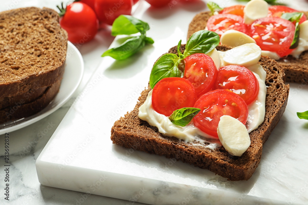 Toast bread with cherry tomatoes and mozzarella cheese on marble board, closeup Toast bread with cherry tomatoes and mozzarella cheese on marble board, closeup