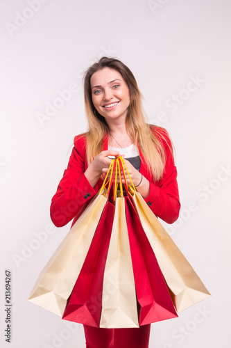 Portrait of happy stylish young woman with shopping bags in red suit