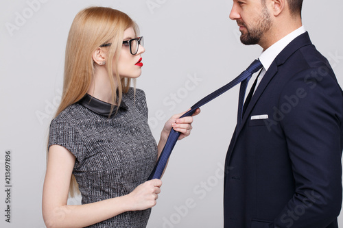 Sexy manipulator woman pulling man by tie