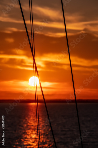 dramatic sunrise over the baltic sea seen through ships ropes and metal railings