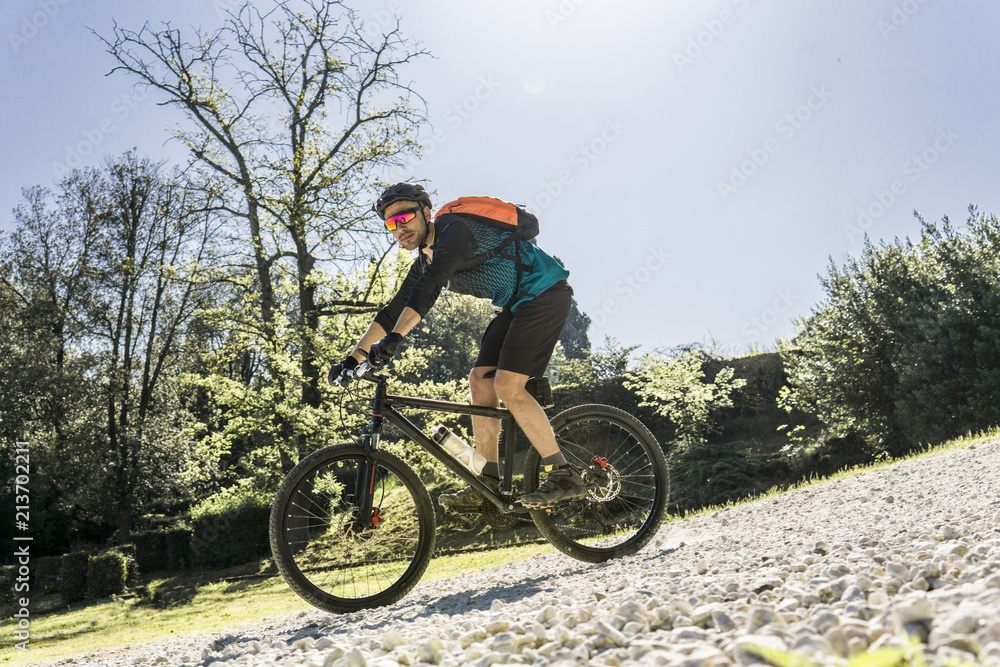 Full length of young man riding mountain bike at park during sunny day Full length of young man riding mountain bike at park during sunny day