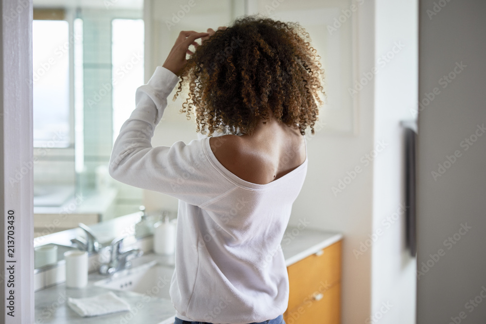 Rear view of woman looking in mirror while standing at home Rear view of woman looking in mirror while standing at home