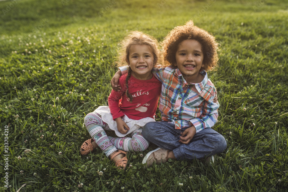 Portrait of happy siblings sitting on grass Portrait of happy siblings sitting on grass