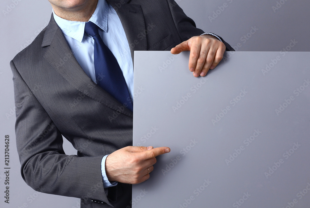Businessman holding a blank board isolated on grey background Businessman holding a blank board isolated on grey background