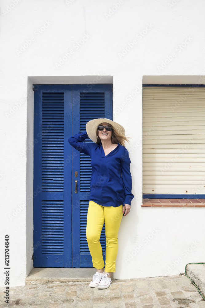 Full length of happy female tourist standing against house in village Full length of happy female tourist standing against house in village