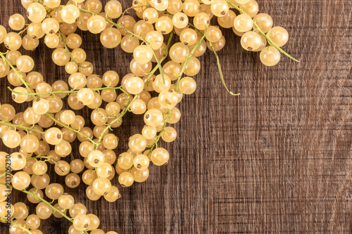 Lot of whole fresh white currant berry blanka variety left upper corner flatlay on brown wood photo