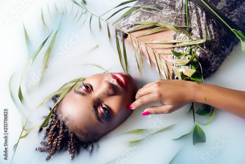 Glamorous African woman with bright make-up and clean skin in milk top view close-up. The
