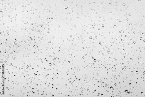 Water drops on transparent glass over white cloudy background. Rain concept
