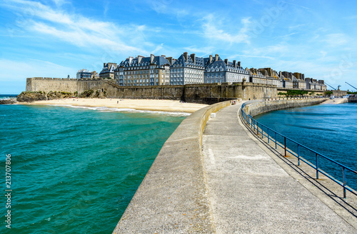 Photo The walled city of Saint-Malo in Brittany, France, with granite residential buildings sticking out above the rampart and the Mole beach at the foot of the fortifications, seen from the breakwater