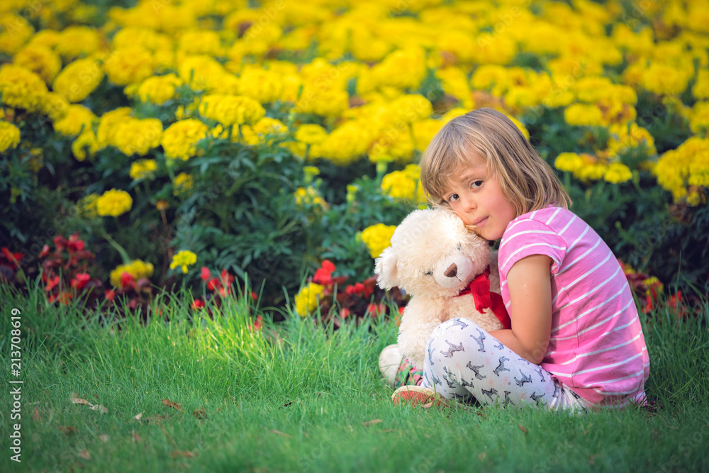 Adorable girl hugging her teddy bear in summer park Adorable girl hugging her teddy bear in summer park