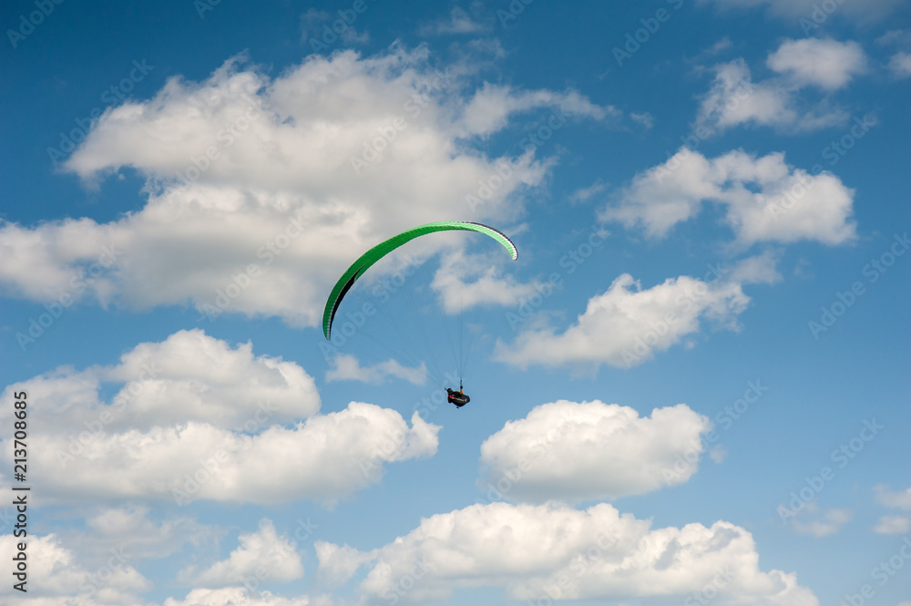 Paraglider flying in the blue sky against the background of clouds. Paragliding in the sky on a sunny day. Paraglider flying in the blue sky against the background of clouds. Paragliding in the sky on a sunny day.