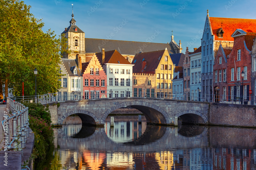 Naklejka premium Malowniczy widok na kanał Brugii z pięknymi średniowiecznymi kolorowymi domami, mostem i odbiciami wieczorem złotej godziny, Belgia