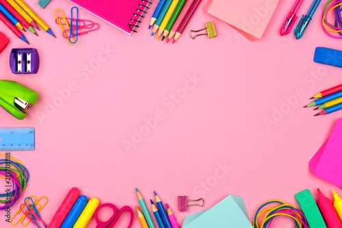 School supplies frame against a pastel pink paper background