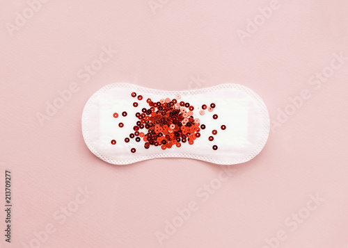 Menstrual pad with red glitter on pastel colored background. Minimalist still life photography concept photo
